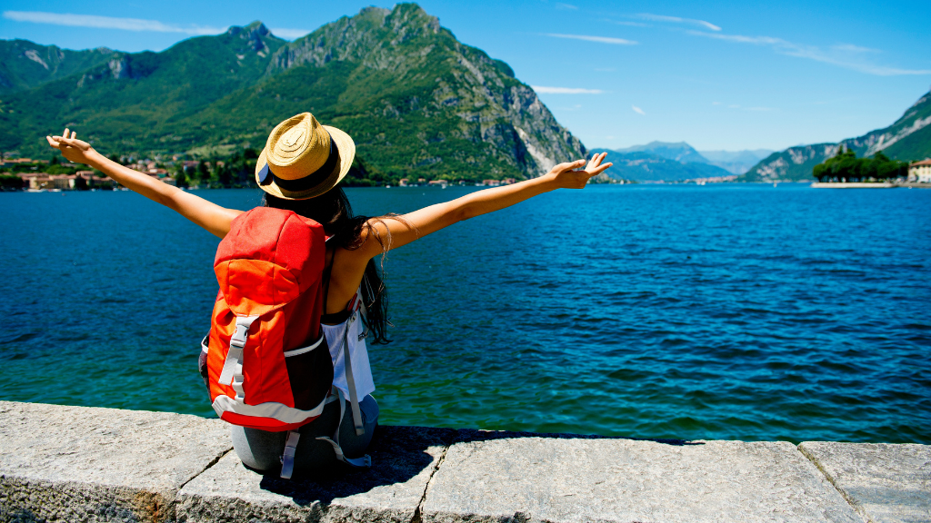 woman with backpack sitting near ocean